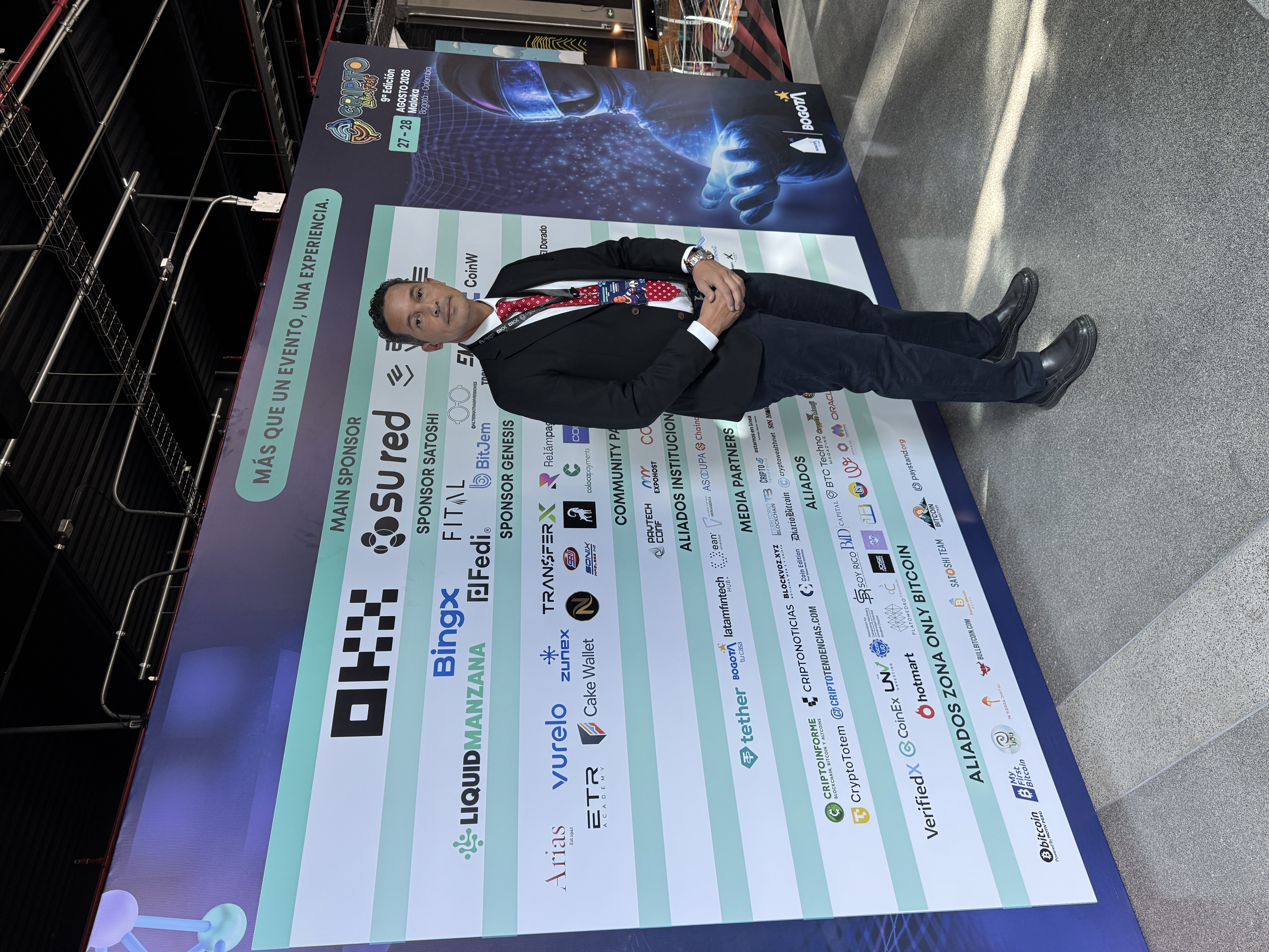 Clemente Acosta con su acreditación frente al mural de Cripto Latin Fest 2026 en Bogotá